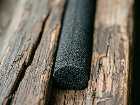 Czarny sznur EPDM spieniony dopasowuje się idealnie do nierównej i spękanej powierzchni starej ościeżnicy, tworząc szczelną barierę.